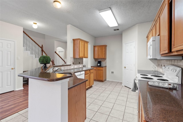 kitchen with tasteful backsplash, sink, light tile patterned floors, white appliances, and a textured ceiling