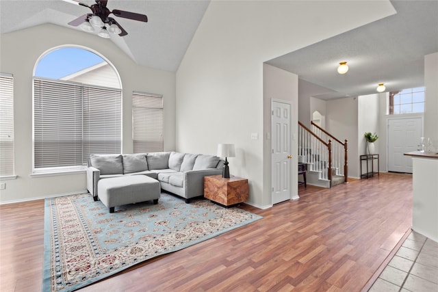 living room featuring high vaulted ceiling, light hardwood / wood-style floors, and ceiling fan