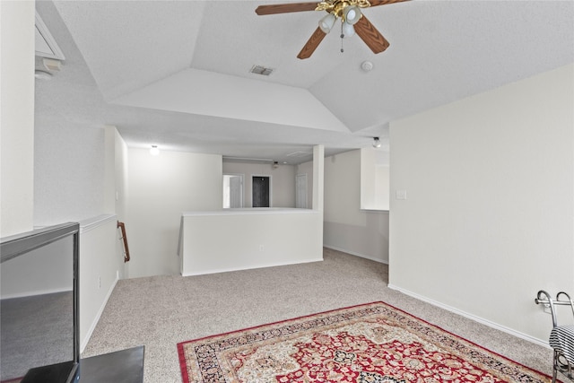 carpeted spare room with a textured ceiling, vaulted ceiling, and ceiling fan