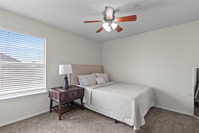 bedroom with ceiling fan, carpet, and a textured ceiling