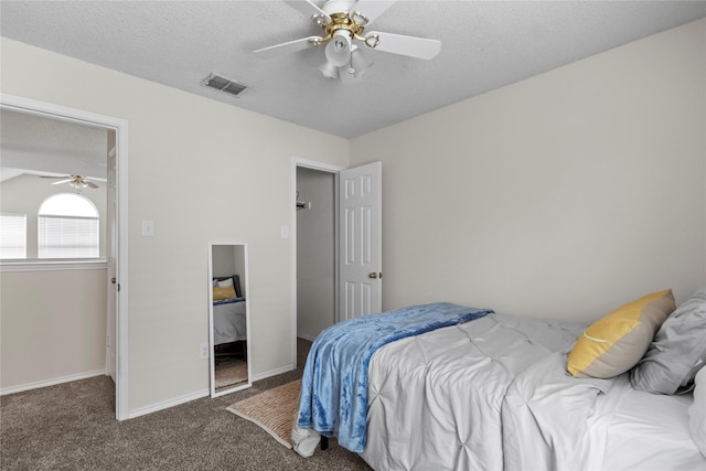 bedroom featuring ceiling fan, dark carpet, and a textured ceiling