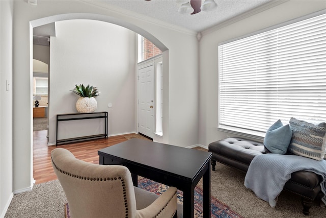 interior space with crown molding, ceiling fan, a textured ceiling, and light hardwood / wood-style flooring