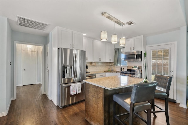 kitchen with sink, white cabinets, hanging light fixtures, a center island, and stainless steel appliances