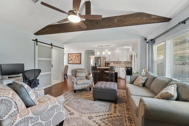 living room featuring hardwood / wood-style floors, lofted ceiling with beams, a barn door, and ceiling fan