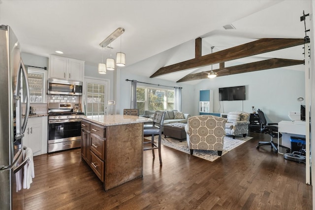 kitchen featuring a kitchen island, appliances with stainless steel finishes, pendant lighting, vaulted ceiling with beams, and white cabinets