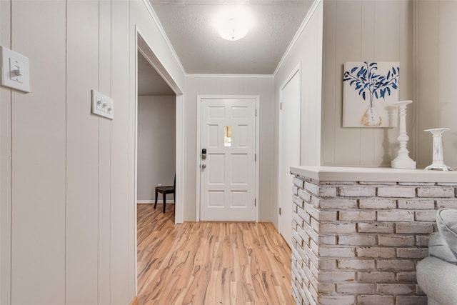 foyer with ornamental molding, a textured ceiling, and light hardwood / wood-style flooring