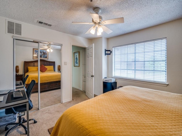 carpeted bedroom featuring ceiling fan, a textured ceiling, and a closet