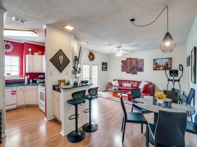 kitchen featuring french doors, hanging light fixtures, a textured ceiling, white appliances, and light hardwood / wood-style floors