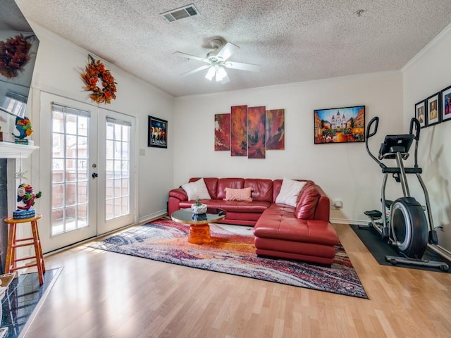 living room with ceiling fan, hardwood / wood-style floors, ornamental molding, a textured ceiling, and french doors