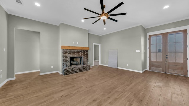 unfurnished living room featuring french doors, crown molding, a brick fireplace, light hardwood / wood-style flooring, and ceiling fan