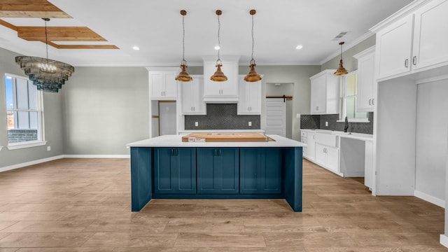 kitchen with decorative light fixtures, white cabinetry, ornamental molding, a center island, and a barn door