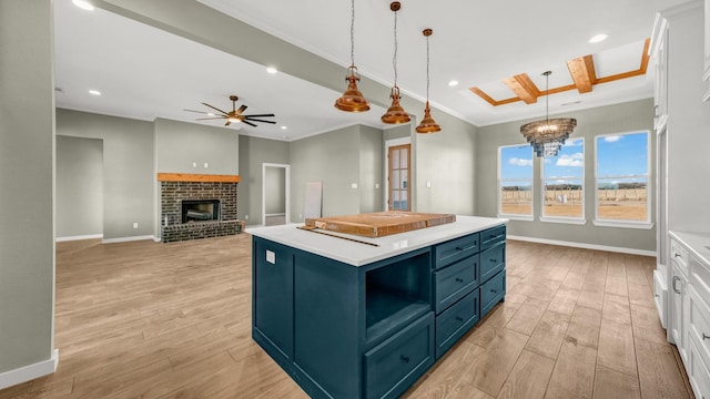 kitchen with pendant lighting, blue cabinetry, white cabinetry, a kitchen island, and ceiling fan with notable chandelier