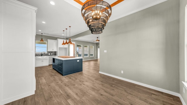 kitchen featuring white cabinetry, a center island, tasteful backsplash, blue cabinets, and decorative light fixtures