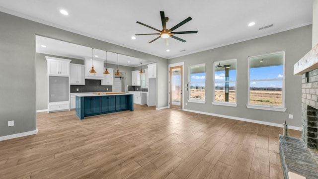 kitchen with blue cabinetry, a fireplace, decorative backsplash, white cabinets, and decorative light fixtures