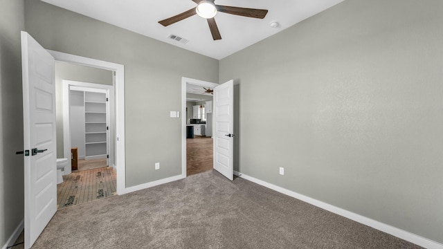 unfurnished bedroom with a walk in closet, carpet floors, ceiling fan, and a closet