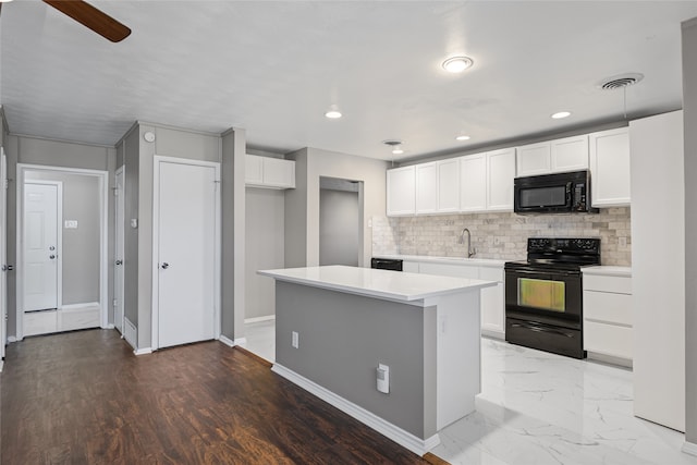 kitchen with tasteful backsplash, sink, white cabinets, a center island, and black appliances