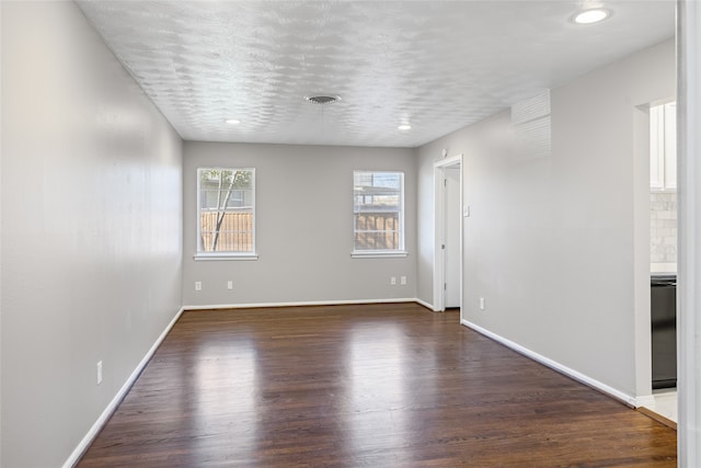 empty room with dark hardwood / wood-style floors and a textured ceiling