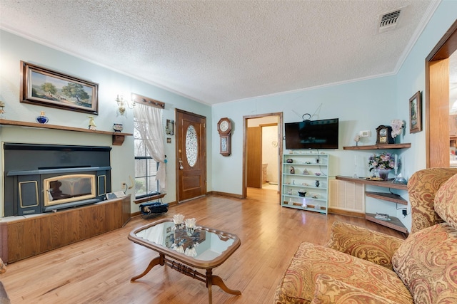 living room with crown molding, a fireplace, light hardwood / wood-style floors, and a textured ceiling