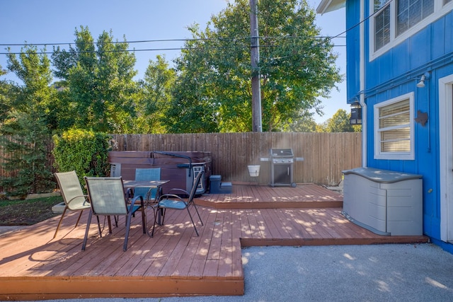 wooden deck with area for grilling and a hot tub