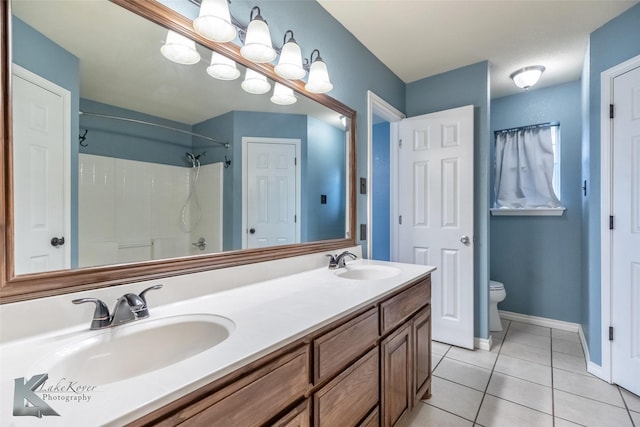 bathroom featuring double vanity, a sink, toilet, and tile patterned floors