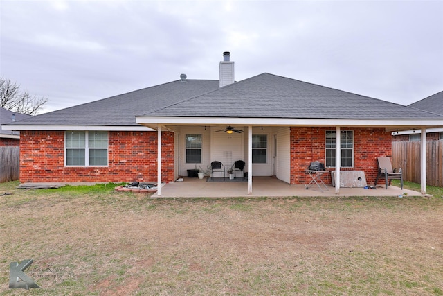 rear view of house with ceiling fan, a patio area, and a lawn