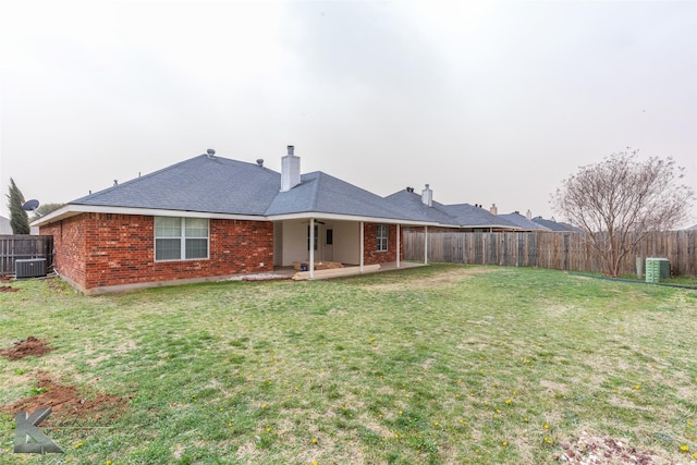 rear view of house with brick siding, central air condition unit, a lawn, a patio area, and a fenced backyard