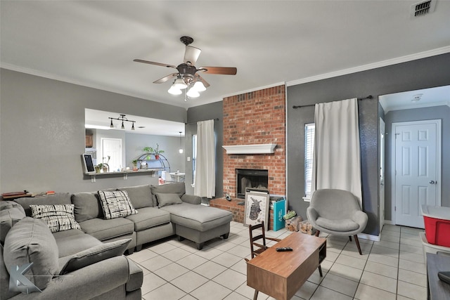 living room featuring crown molding, ceiling fan, a fireplace, and light tile patterned floors