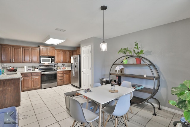 kitchen with stainless steel appliances, light tile patterned flooring, sink, and pendant lighting