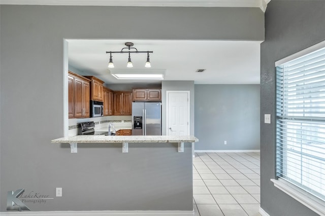 kitchen featuring light tile patterned floors, visible vents, appliances with stainless steel finishes, a peninsula, and a kitchen bar