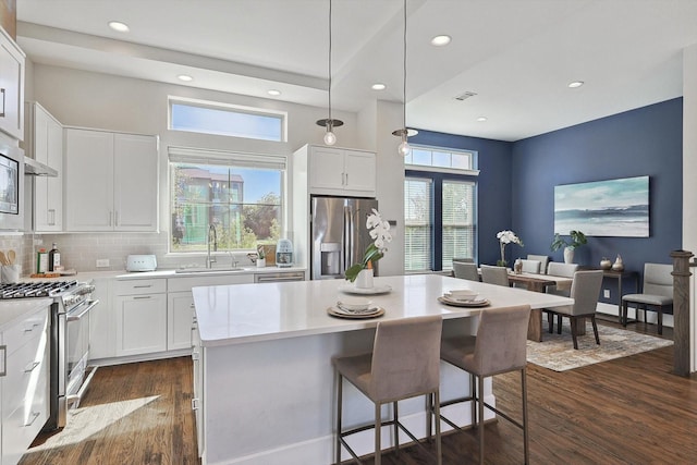 kitchen featuring sink, appliances with stainless steel finishes, a center island, white cabinets, and dark hardwood / wood-style flooring