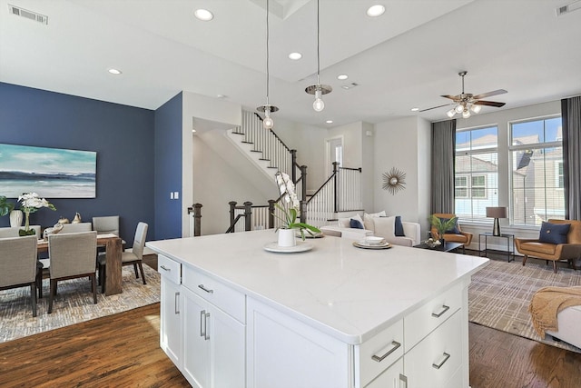 kitchen with decorative light fixtures, dark hardwood / wood-style floors, a center island, and white cabinets