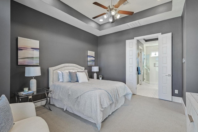 bedroom featuring light colored carpet, a raised ceiling, and ceiling fan