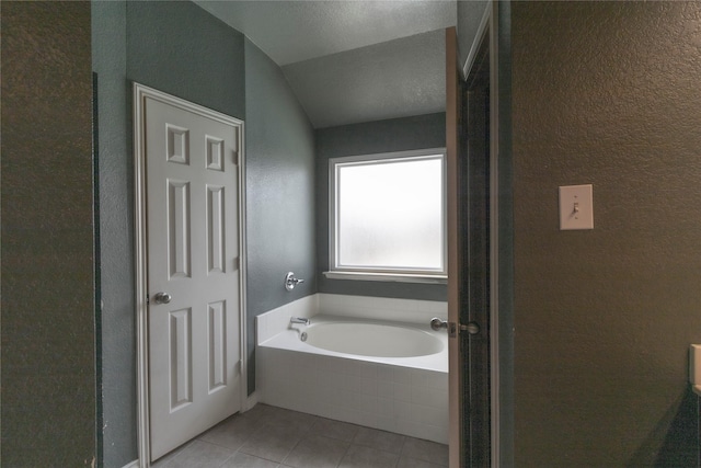 bathroom featuring tiled tub, vaulted ceiling, and tile patterned floors