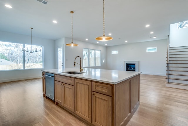 kitchen with pendant lighting, sink, light hardwood / wood-style flooring, a wealth of natural light, and an island with sink