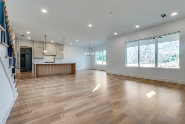 unfurnished living room featuring light hardwood / wood-style floors and a notable chandelier