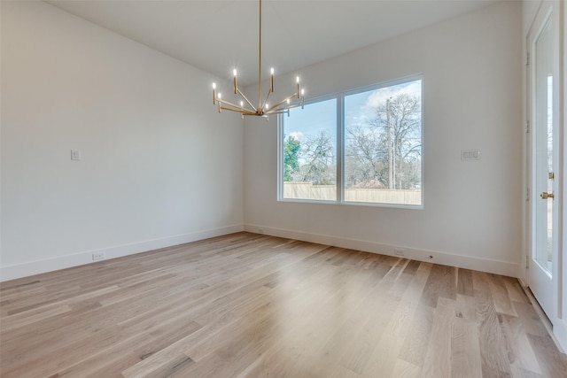 unfurnished dining area featuring an inviting chandelier and light hardwood / wood-style floors