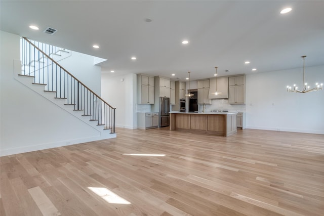 unfurnished living room with a notable chandelier and light wood-type flooring