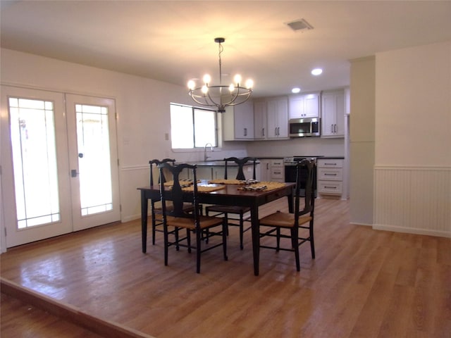 dining room featuring an inviting chandelier, light hardwood / wood-style floors, and french doors