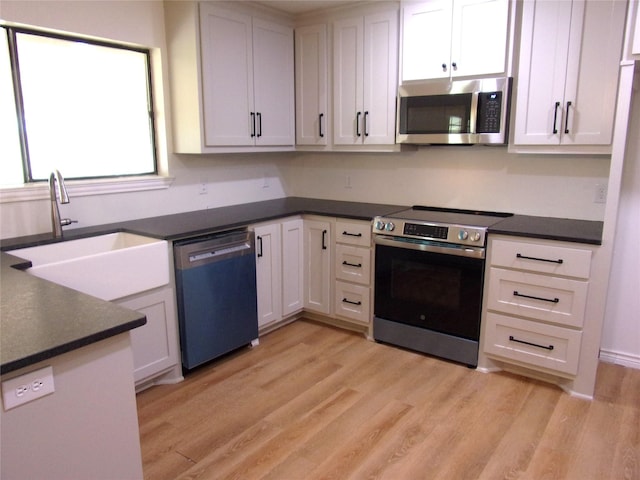 kitchen featuring stainless steel appliances, light hardwood / wood-style floors, sink, and white cabinets