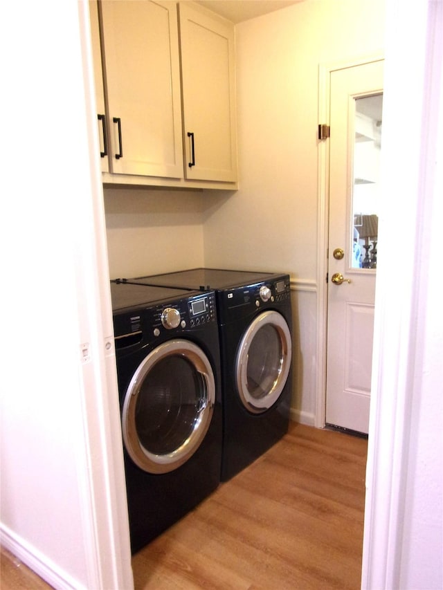 washroom with washer and clothes dryer, cabinets, and light wood-type flooring