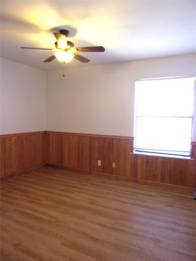 unfurnished room with dark wood-type flooring, ceiling fan, and wood walls