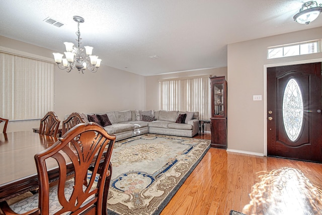 entrance foyer featuring an inviting chandelier, a textured ceiling, and light wood-type flooring