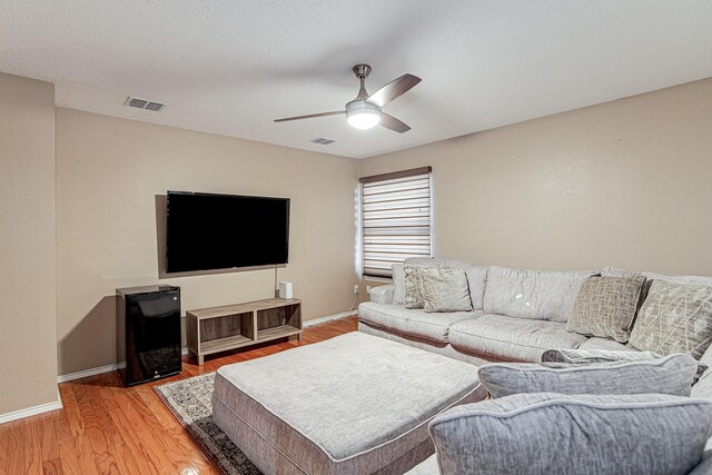 living area with light wood-type flooring, visible vents, and baseboards