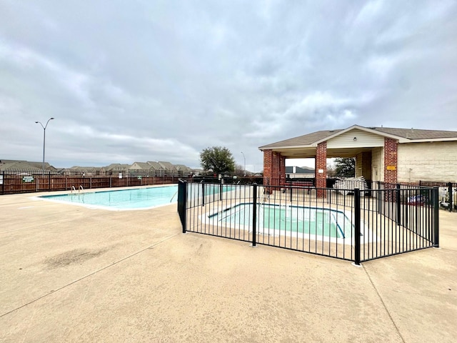 community pool with a patio area and fence