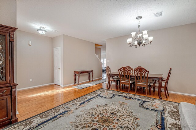 dining space with visible vents, baseboards, light wood-style floors, and a notable chandelier