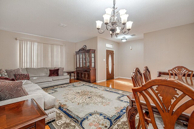 living area with visible vents, a textured ceiling, wood finished floors, and a chandelier