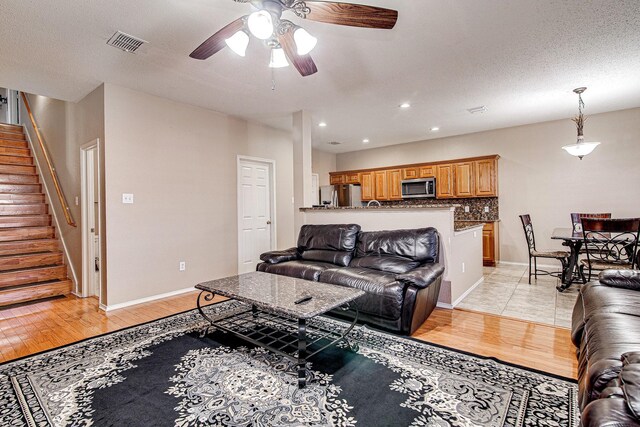 living area featuring visible vents, baseboards, light wood-style flooring, and stairs