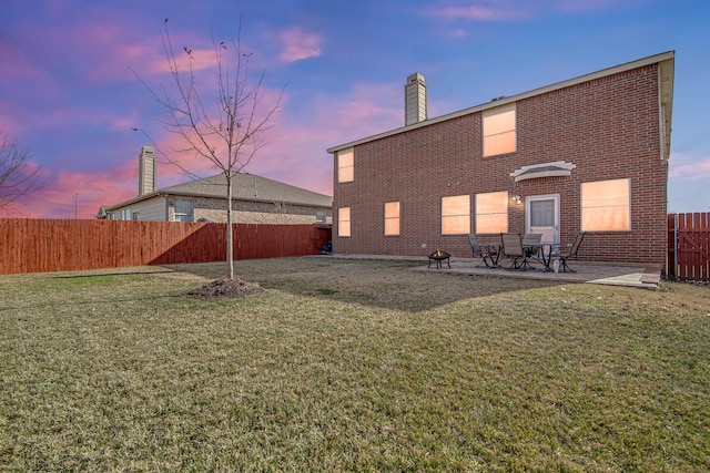 back of property featuring brick siding, a patio area, a lawn, and a fenced backyard