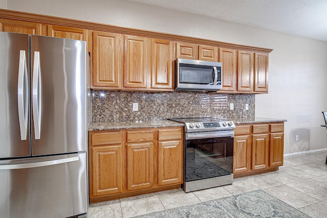 kitchen featuring brown cabinetry, stainless steel appliances, stone counters, and decorative backsplash