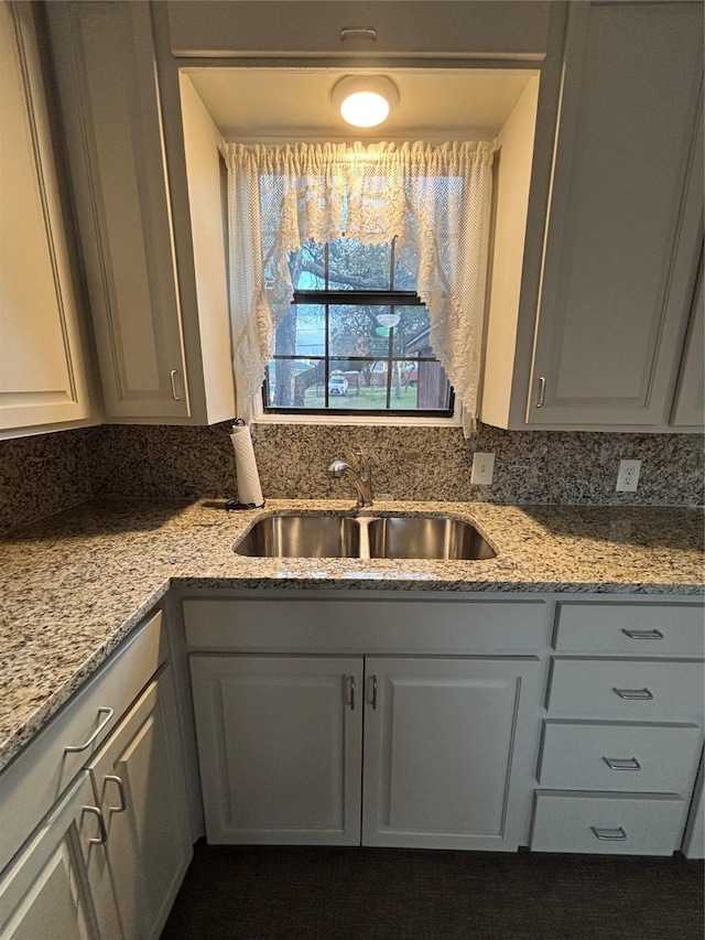 kitchen with gray cabinets, tasteful backsplash, light stone countertops, and sink